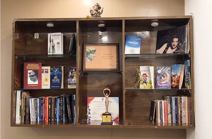 Bookshelf displaying published books, awards, and author achievements at a professional book publishing office.